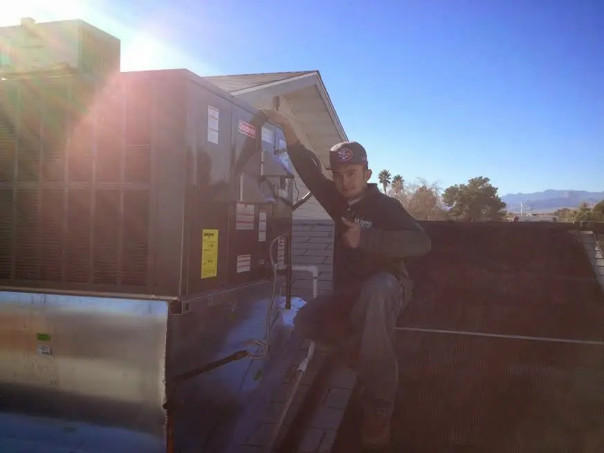 HVAC technician performing AC Tune-Up on a rooftop unit in Bolton